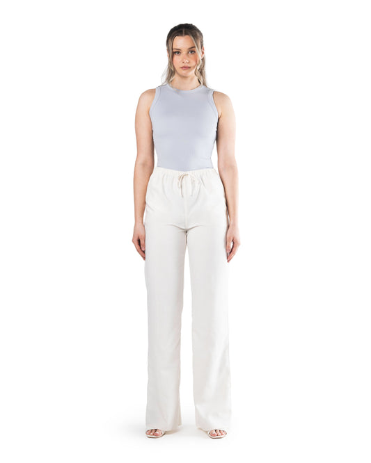 A tall model wearing tall linen trousers on a white back drop and a tall blue vest