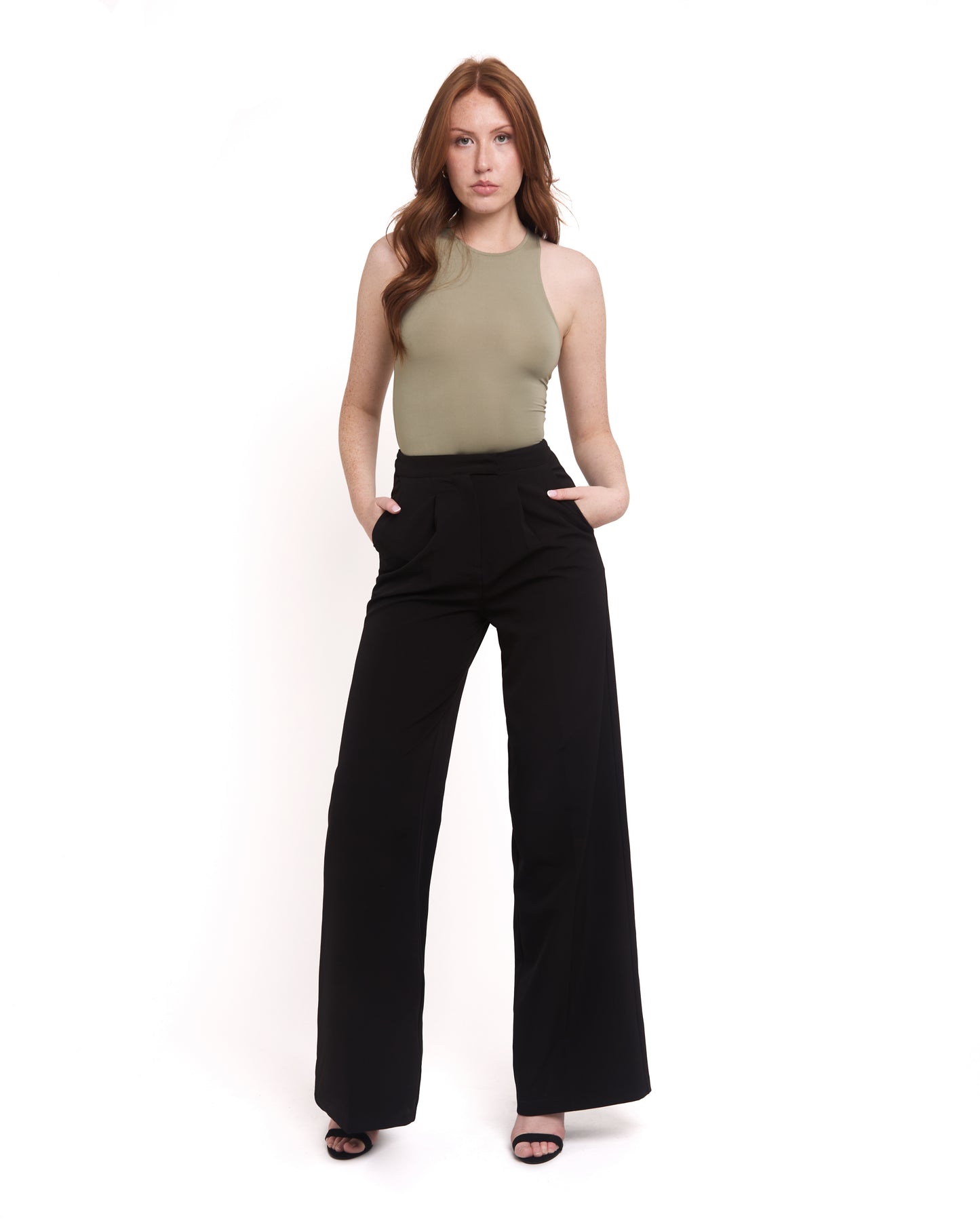 A model wearing tall wide leg tailored trousers in black with a high-waisted fit and a sleek silhouette.The Model has hands in both pockets