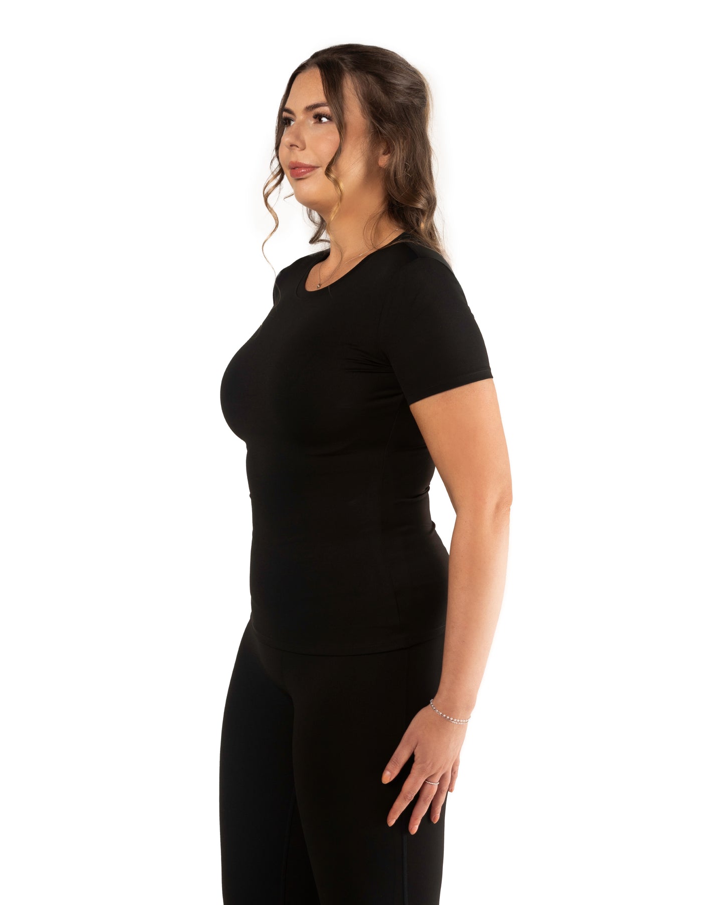 A side shot model wearing a tall short sleeve active t-shirt in black colour, posing with hands on hips.