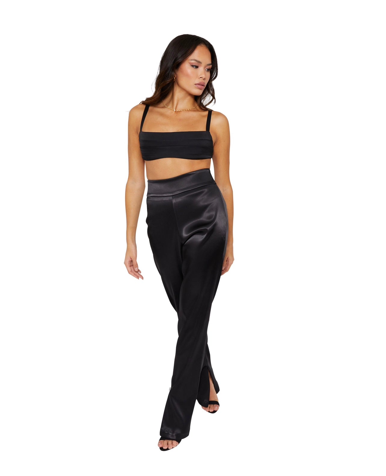 A Tall model wearing high waisted satin trousers with a straight leg cut, featuring a back zip and hook closure, and leg zip detailing.