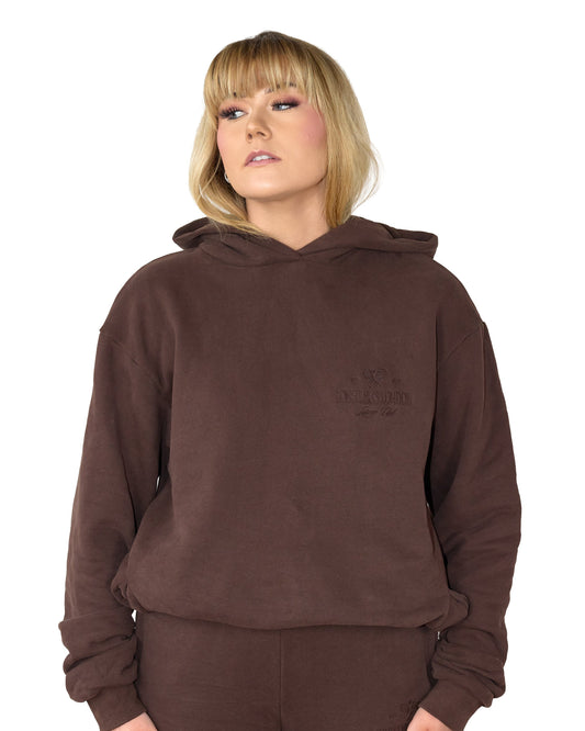 Person wearing a brown hoodie and pants on a white background