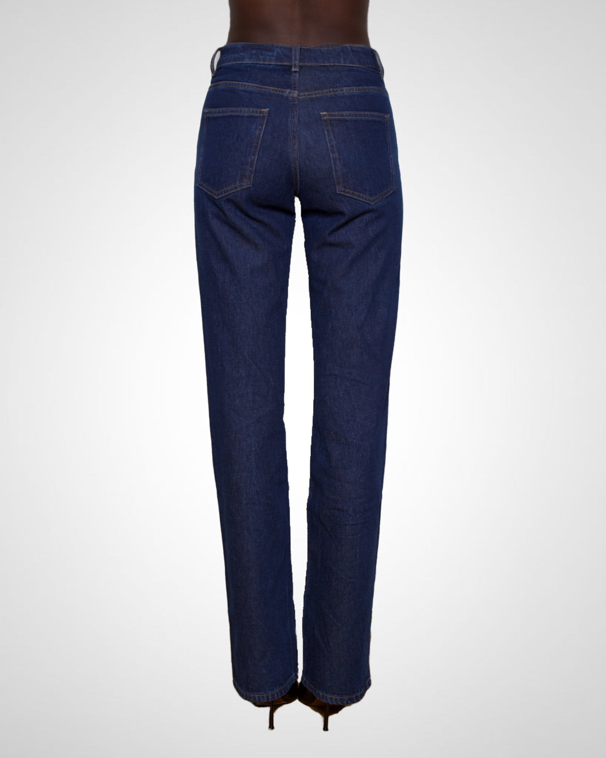 Rear view of a model wearing dark blue straight-leg denim jeans with a high waist and back pockets, shown against a light gray studio background.