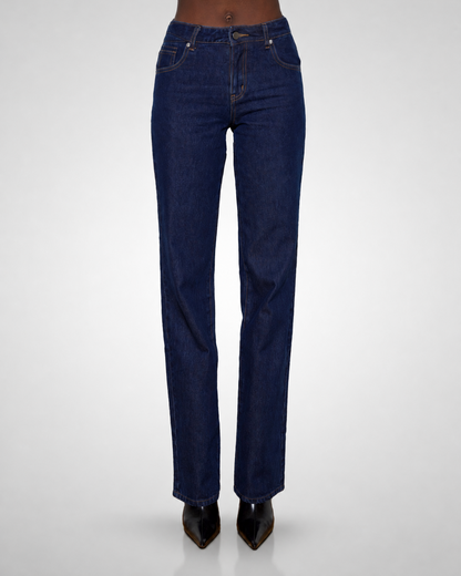 A tall model is shown from the waist down wearing dark blue straight-leg denim jeans and black pointed-toe heels, photographed against a light gray studio background.
