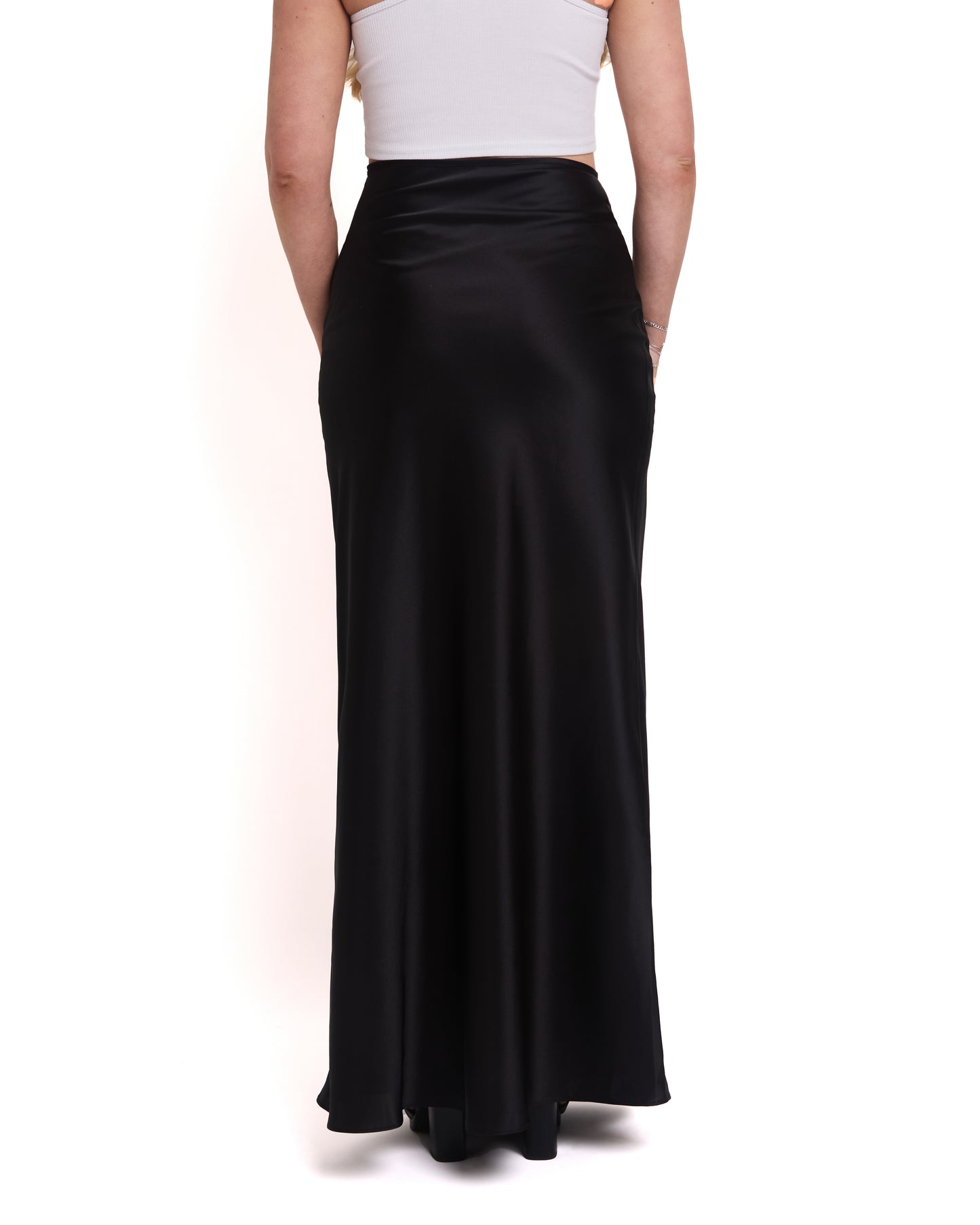 A model wearing a tall, high-waisted, tailored black maxi skirt with a high waist and invisible side zip. Back shot