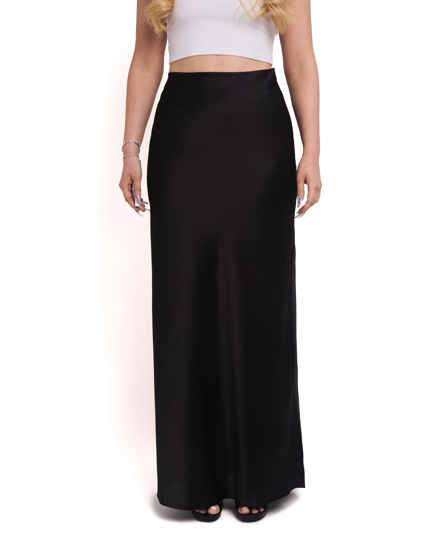 A tall model wearing a tall, high-waisted, tailored black maxi skirt with a high waist and invisible side zip.