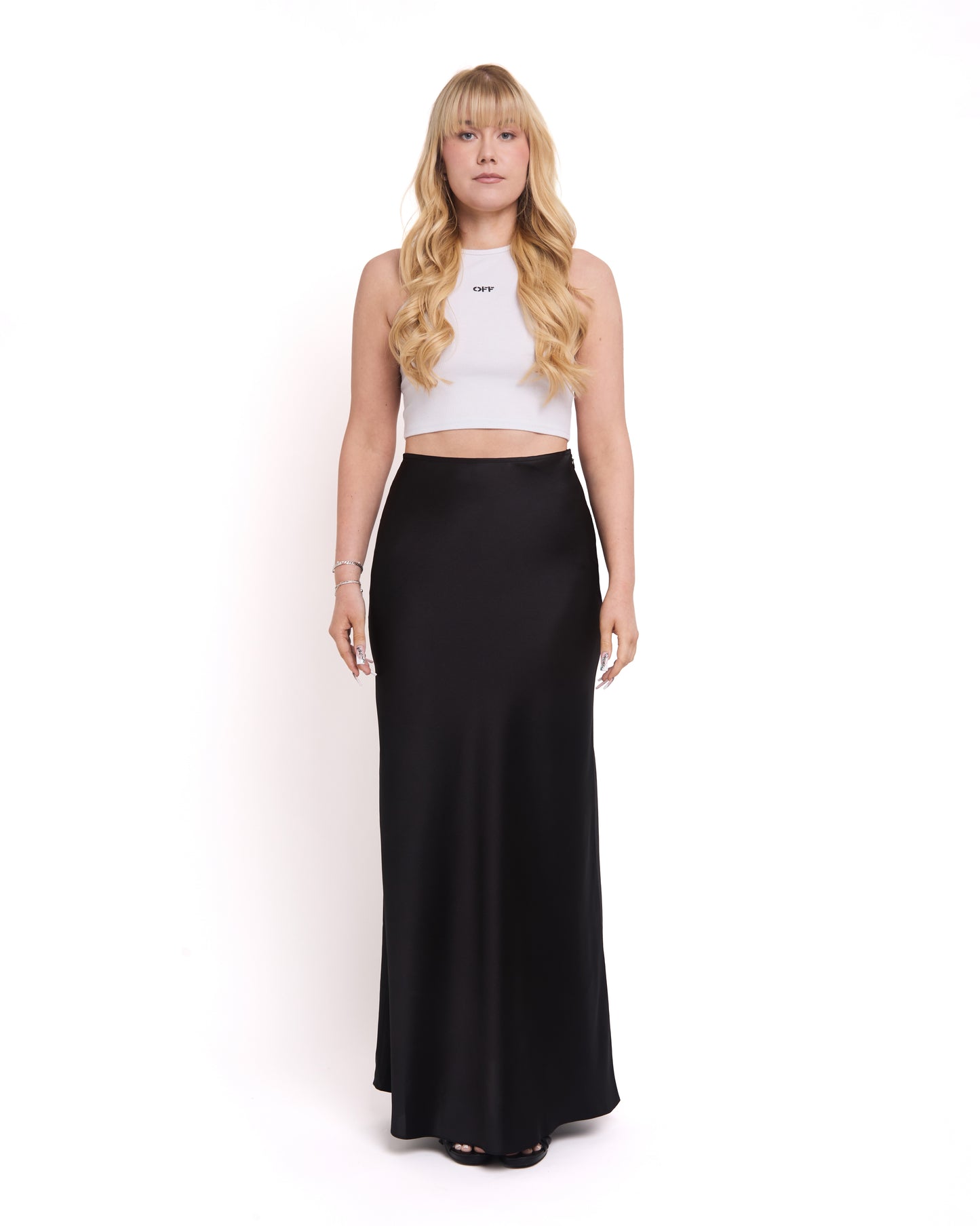 A model wearing a tall, high-waisted, tailored black maxi skirt with a high waist and invisible side zip.
