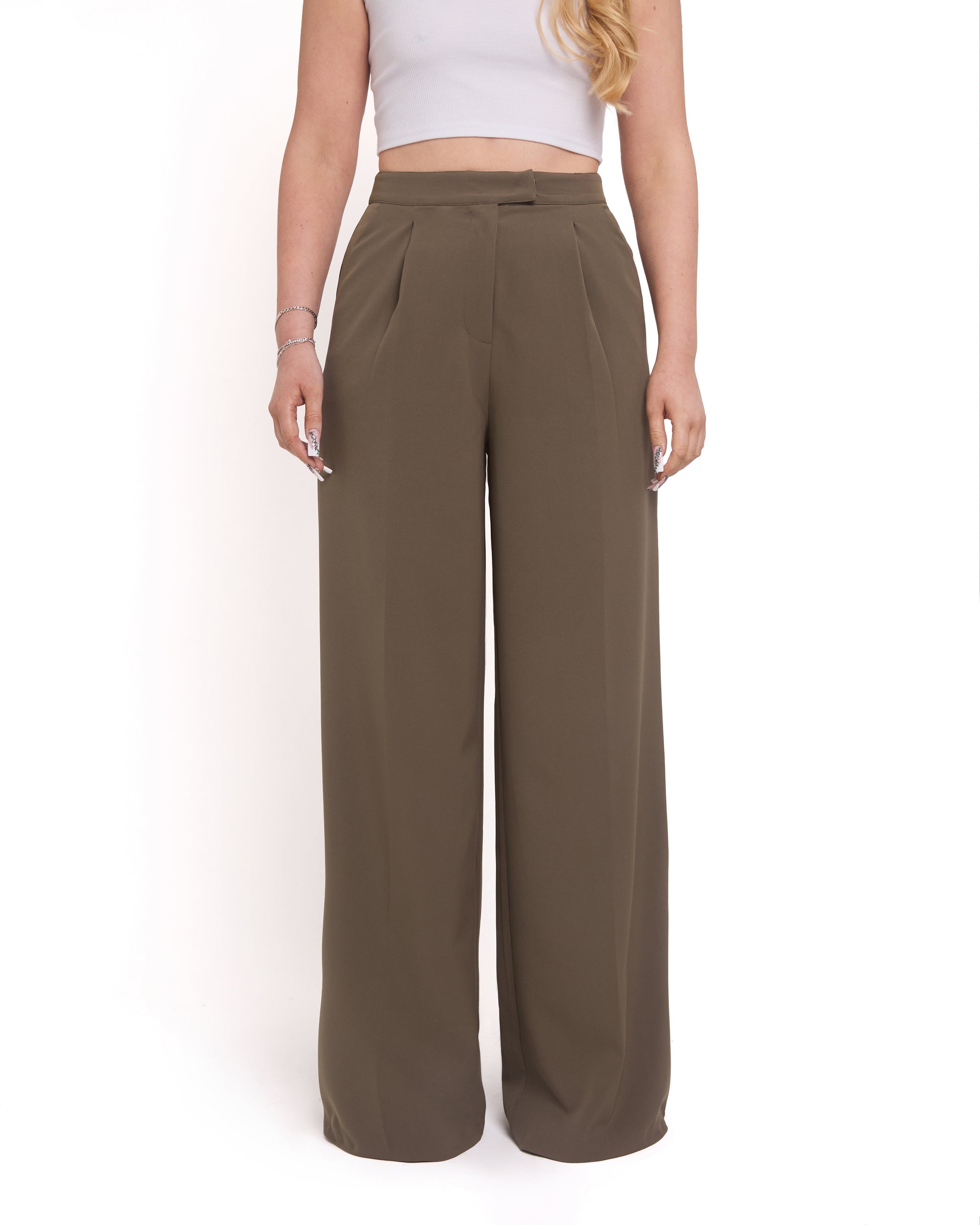 A woman standing against a white background, wearing tall wide-leg tailored trousers in olive green color with a high-waisted fit.