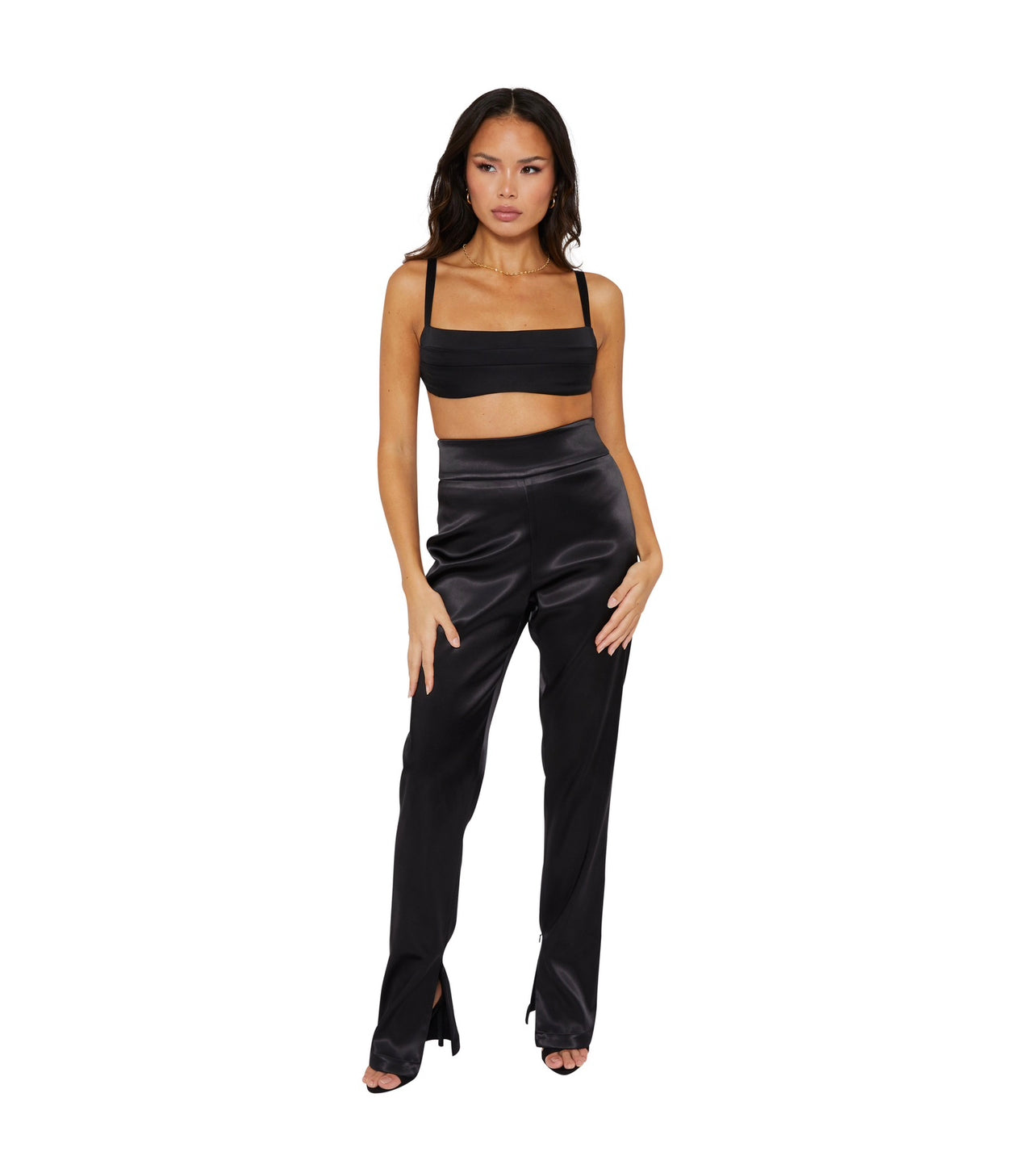 A Tall model wearing high waisted satin trousers with a straight leg cut, featuring a back zip and hook closure, and leg zip detailing.