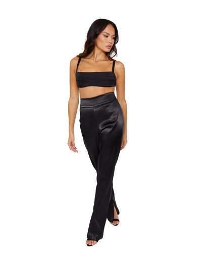 A Tall model wearing high waisted satin trousers with a straight leg cut, featuring a back zip and hook closure, and leg zip detailing.