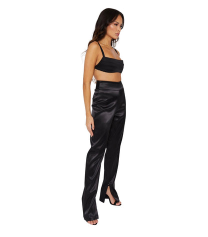 A Tall model wearing high waisted satin trousers with a straight leg cut, featuring a back zip and hook closure, and leg zip detailing. Standing to the side