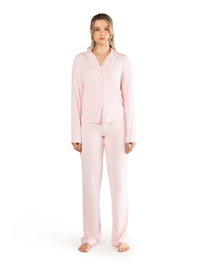 A model wearing tall pink high waisted pyjama bottoms with a matching long sleeve top, standing against a white background.